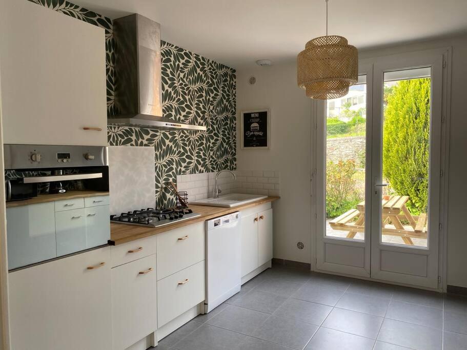 a kitchen with white cabinets and a large window at Maison Village de La Verrerie in Cherbourg en Cotentin