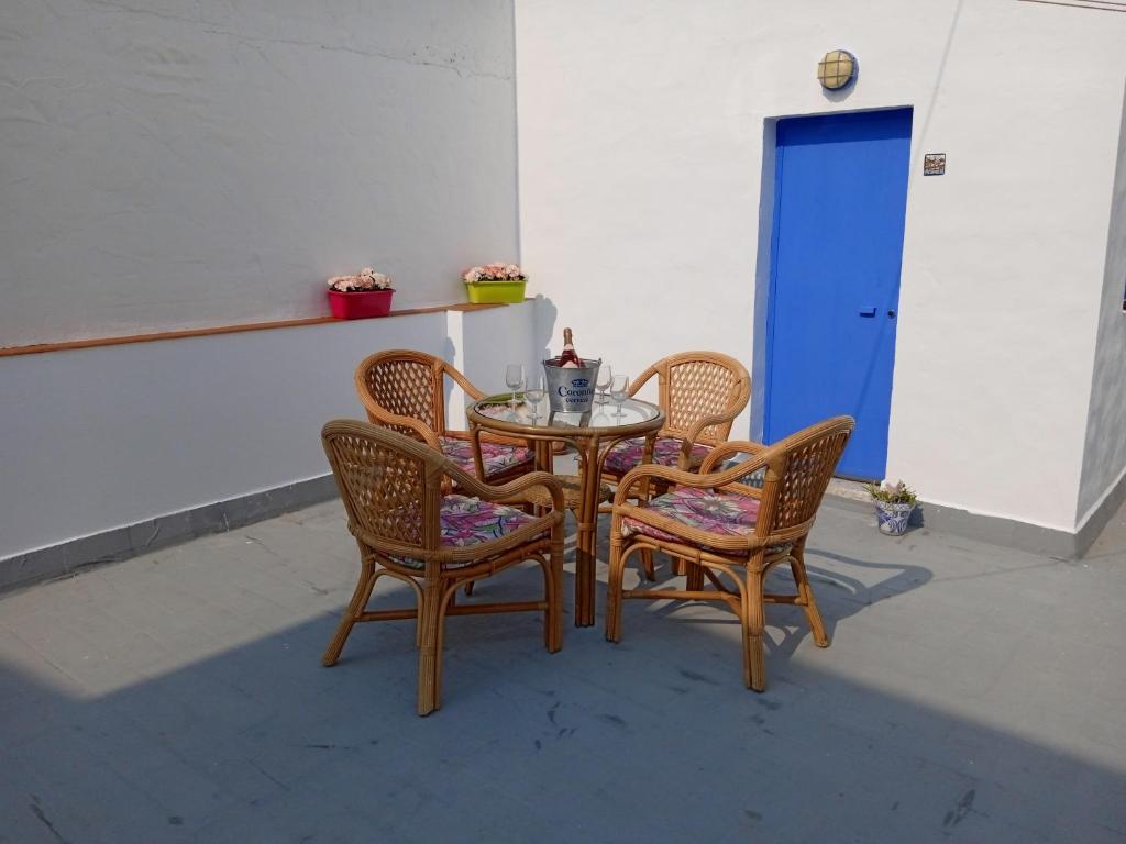 una mesa con 4 sillas y una puerta azul en Apartamento de las Flores en Conil, en Conil de la Frontera