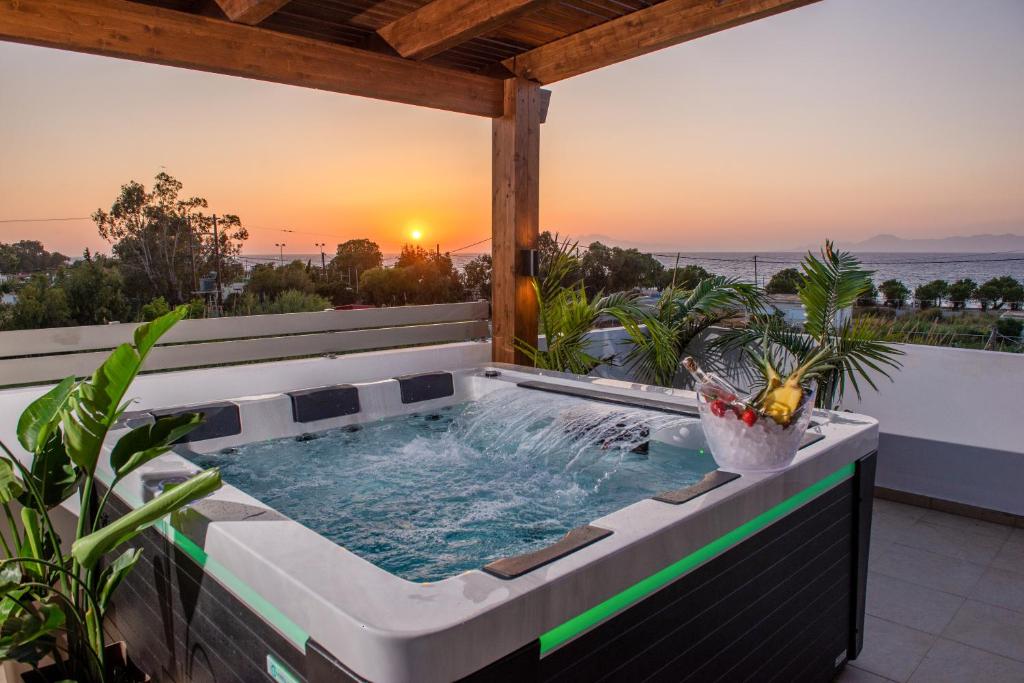 a hot tub on a balcony with the sunset in the background at ODYSSEA Top View & Hot Jacuzzi Front Beach in Kremasti