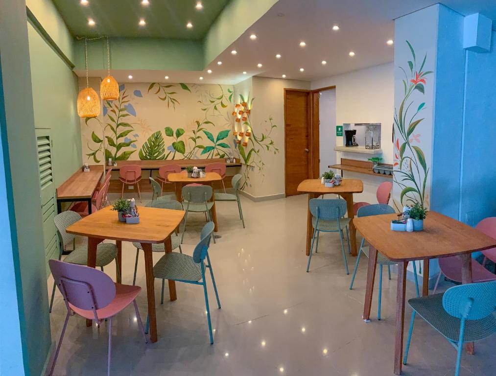 un restaurante con mesas y sillas y una pared con plantas en Infinity Hotel, en Medellín