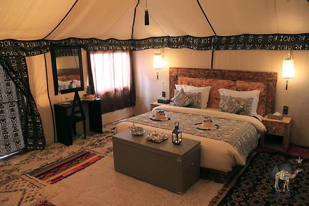 エルフードにあるMerzouga dreams Campのベッドルーム(大型ベッド1台、テーブル付)
