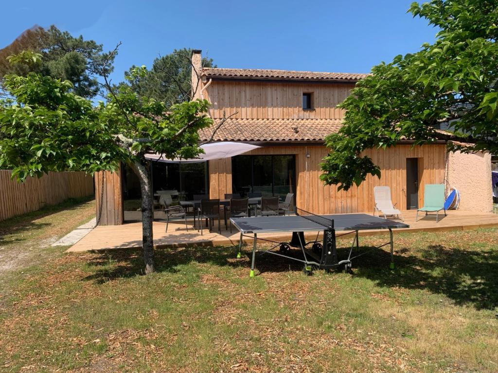 un patio avec une table et un parasol dans l'établissement Villa - Montalivet les bains - 450m Océan, à Vendays-Montalivet