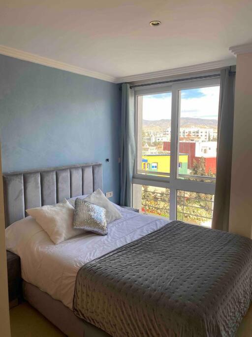 - une chambre avec un lit et une grande fenêtre dans l'établissement appartement neuf ensoleillé avec parking sous sol, à Agadir