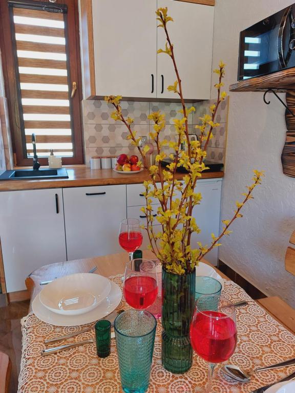 a table with wine glasses and a vase with flowers at Domek pod Holicą 3 in Ustianowa