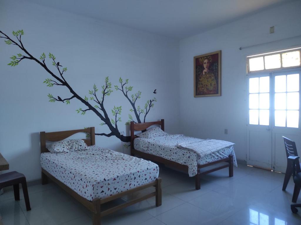 a room with two beds and a tree on the wall at 717 Pizarro guesthouse in Trujillo