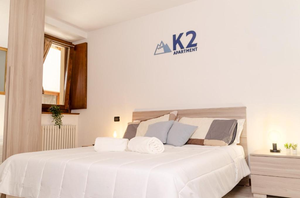 a white bedroom with a large bed with white sheets at K2 Apartment in Aosta