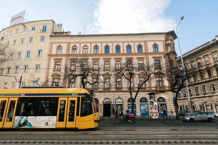un autobús amarillo conduciendo por una calle frente a un edificio en Center of the City, - it's only yours, with two bedrooms, 1 price for 3, en Budapest