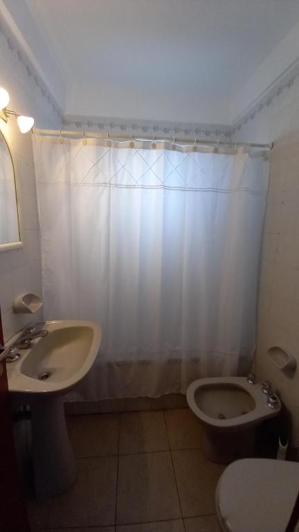 a bathroom with a sink and a toilet and a shower curtain at Departamentos 3 Ambientes Cochera Punta Mogotes in Mar del Plata