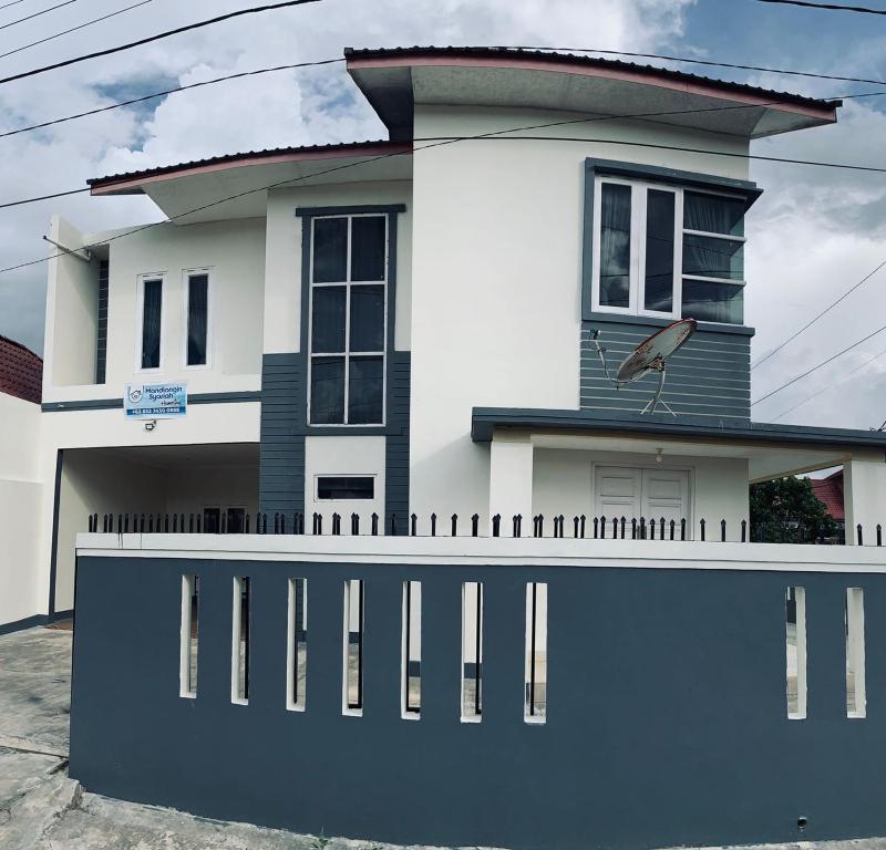 a white house with a fence in front of it at Mandi Angin "Syariah" Homestay in Bukittinggi