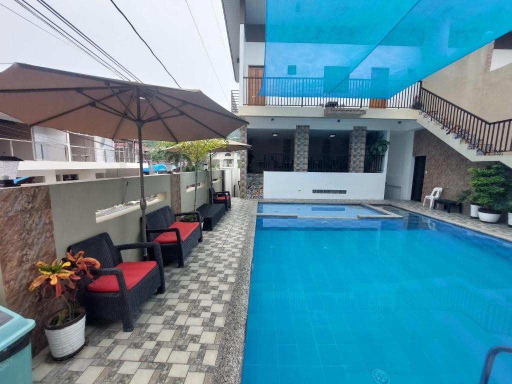 a swimming pool with chairs and an umbrella at Ma Garbo Hotspring Private Resort in Calamba