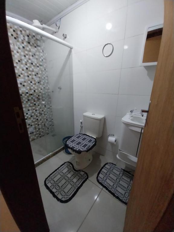 uma casa de banho com um WC, um chuveiro e 2 tapetes. em Casa 4 em Campos dos Goytacazes