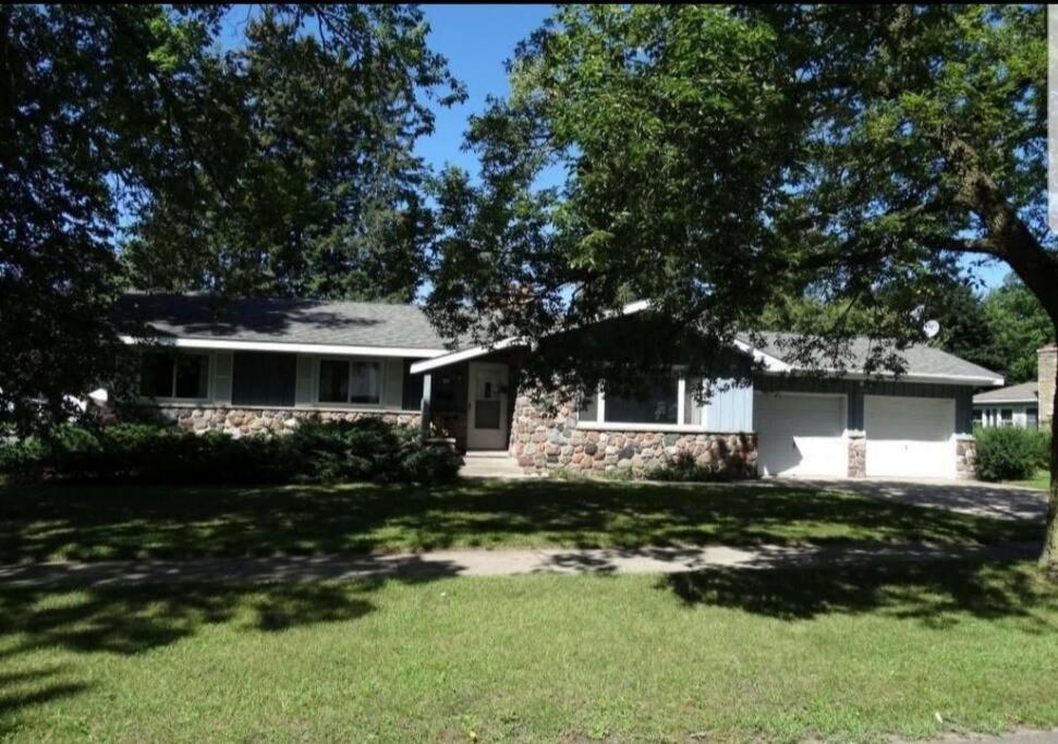 a house with a tree in front of a yard at Entire home 5min to Senior Open+Breakfast! in Stevens Point