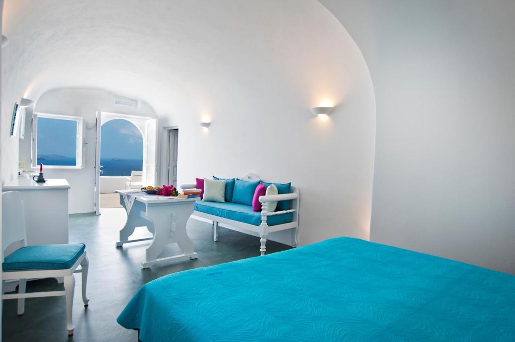 a bedroom with a blue bed and a table and chairs at Thirea Studios in Oia