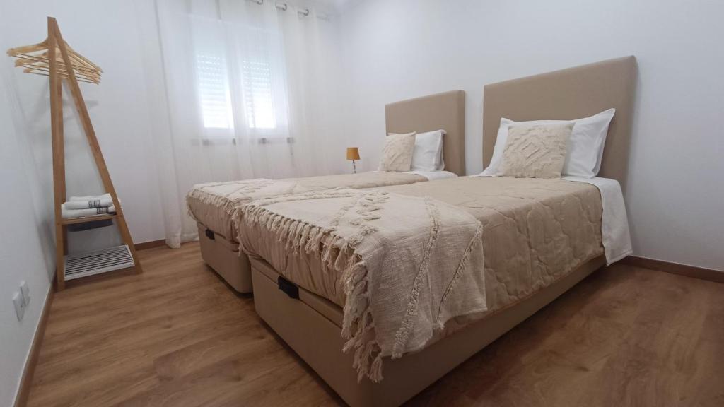 a bedroom with two beds with white walls and wood floors at Mondalva Apartamentos in São Pedro de Alva