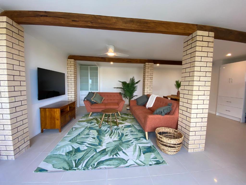 a living room with a couch and a television and a rug at Wave Cave Suite in Coffs Harbour