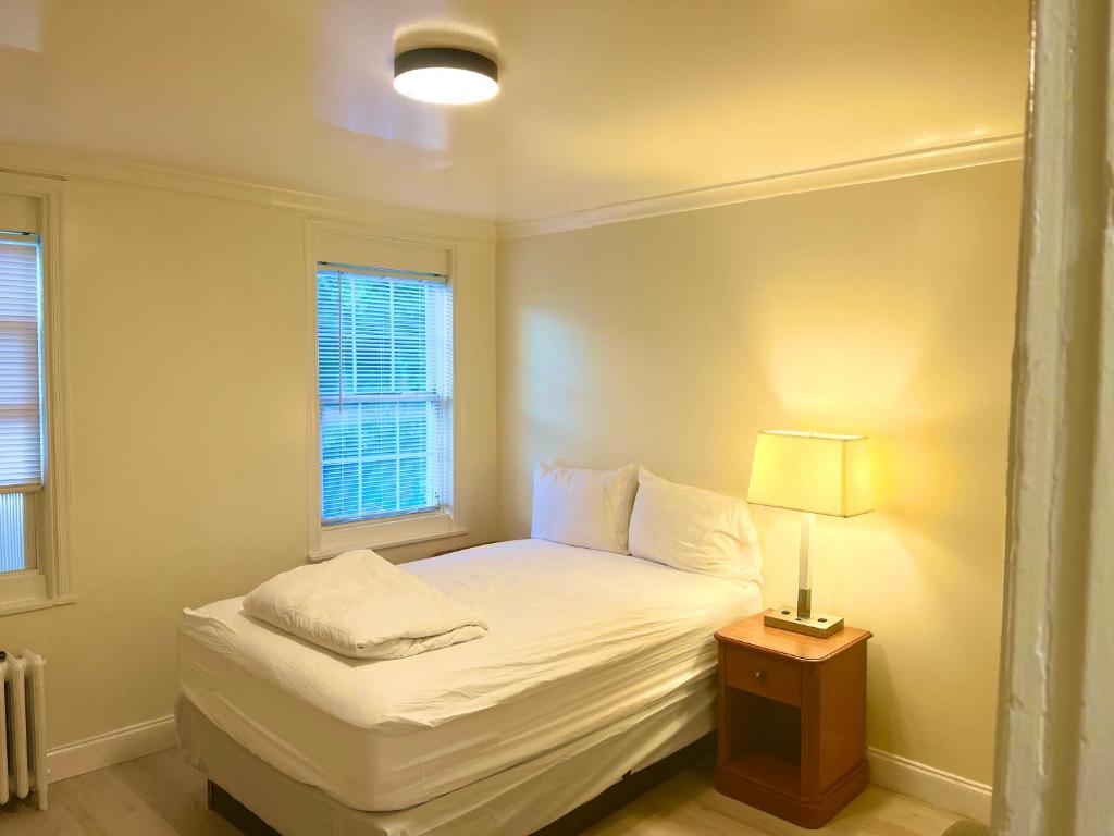 BedExpress في بالتيمور: غرفة نوم صغيرة بها سرير أبيض ومصباح