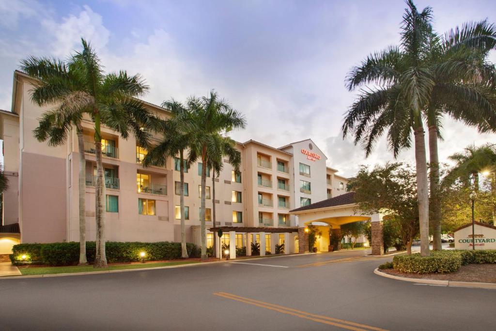 a hotel with palm trees in front of a street at Courtyard Fort Lauderdale SW Miramar in Miramar