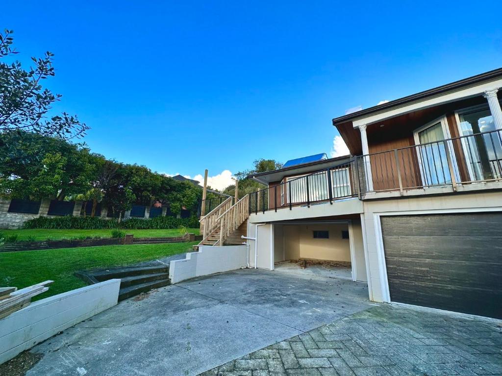 a house with a garage door and a balcony at Elegant House in East Auckland in Auckland