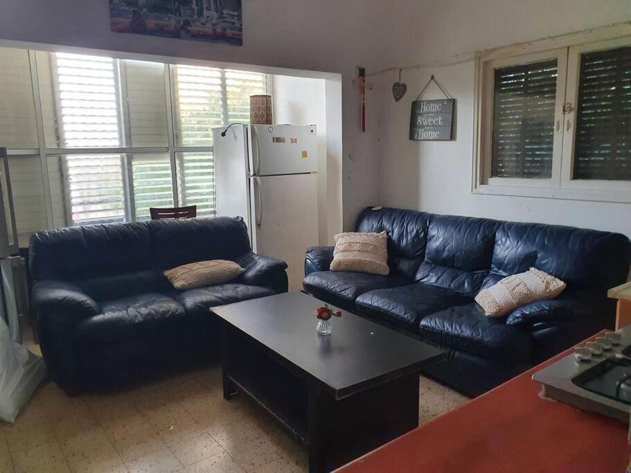 - un salon avec des canapés en cuir noir et une table dans l'établissement 2 bedroom apartment in batiya makov, à Rechovot