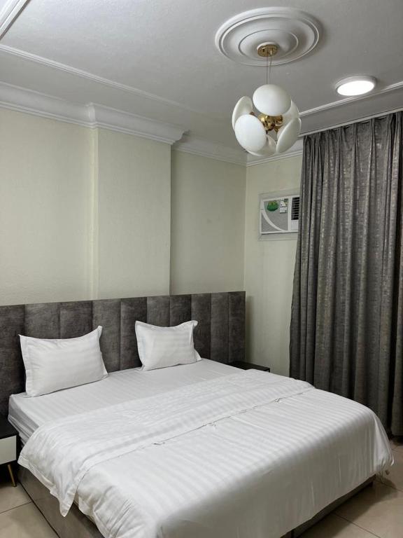 a bedroom with a large white bed and a ceiling fan at بيوتي روز لشقق المخدومه in Abha
