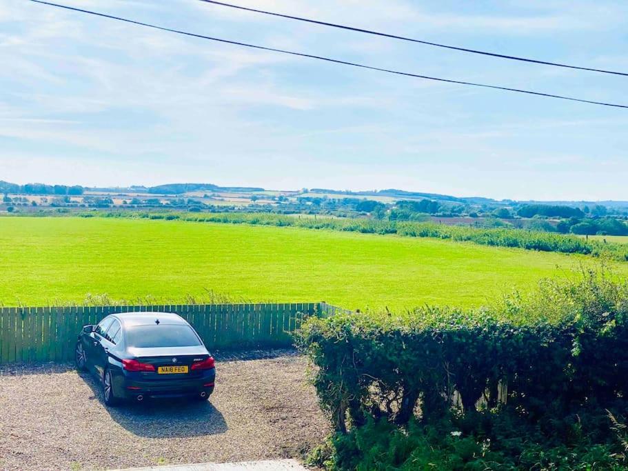 a car parked in front of a green field at Hare view Cottage - Northumberland 