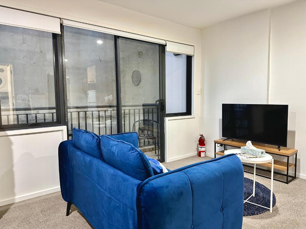 ein Wohnzimmer mit einem blauen Sofa und einem TV in der Unterkunft Cozy 1-bedroom unit at CBD in Auckland