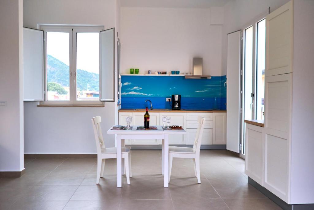 a white kitchen with a white table and chairs at Vento di Mare in Piraino