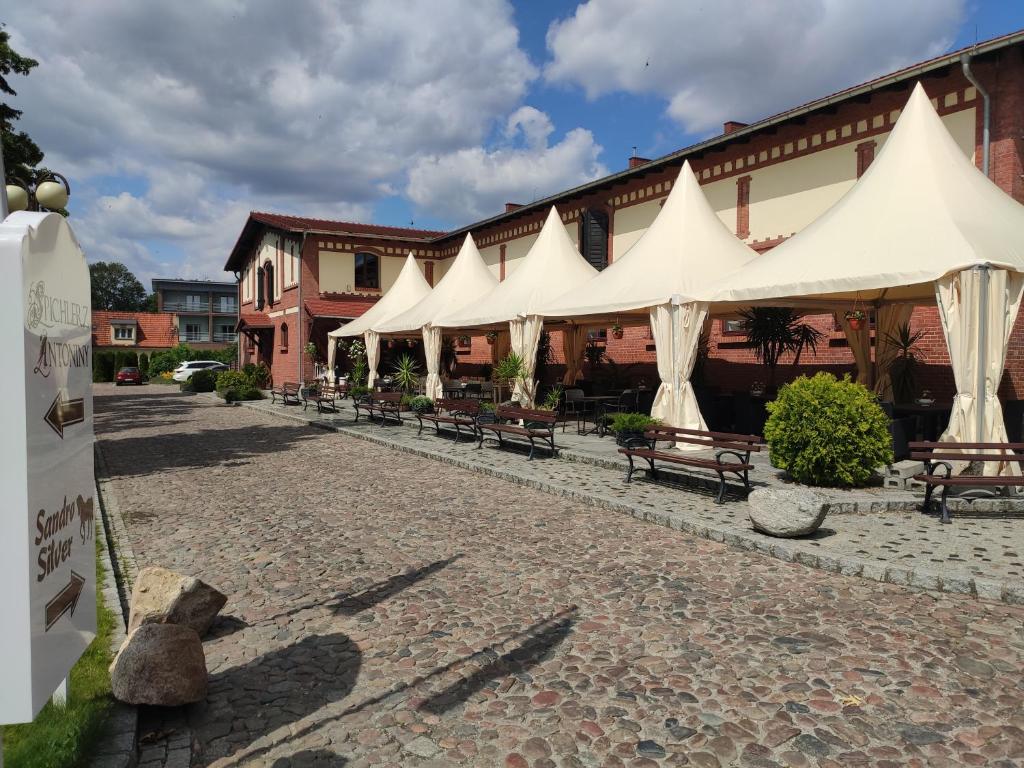 un patio con sombrillas y bancos blancos frente a un edificio en Hotel Sandro Silver en Leszno