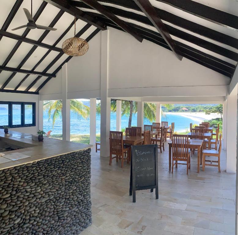 a restaurant with tables and chairs and the ocean at Balong Balong Surf Bungalows & Restaurant in Sekongkang