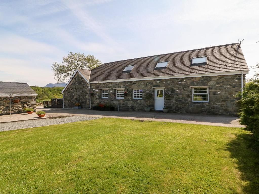 een oud stenen huis met een grasveld bij Bodrual Cottage in Caernarfon