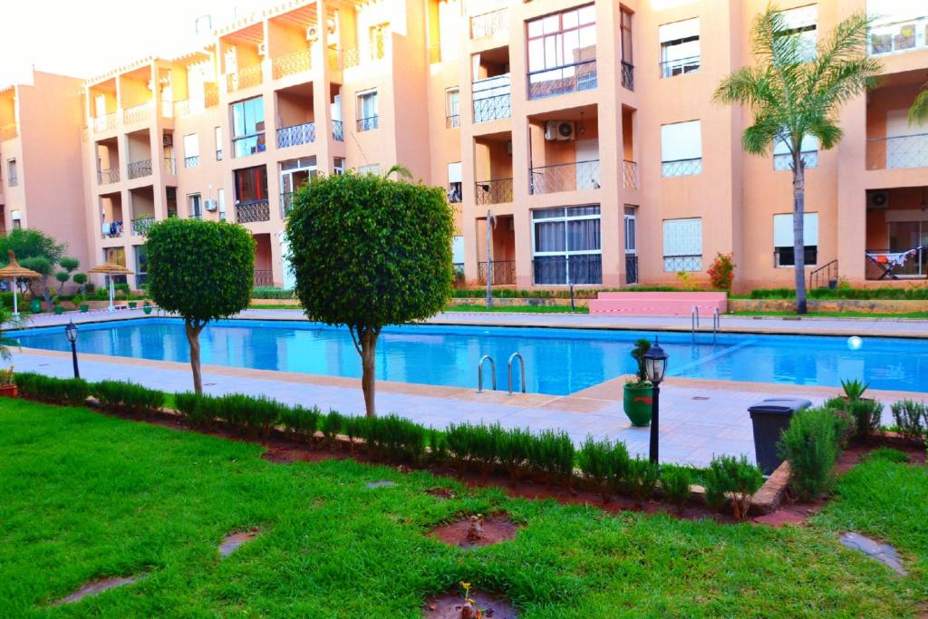 - une piscine en face d'un immeuble dans l'établissement Reco flores PALM, à Benslimane