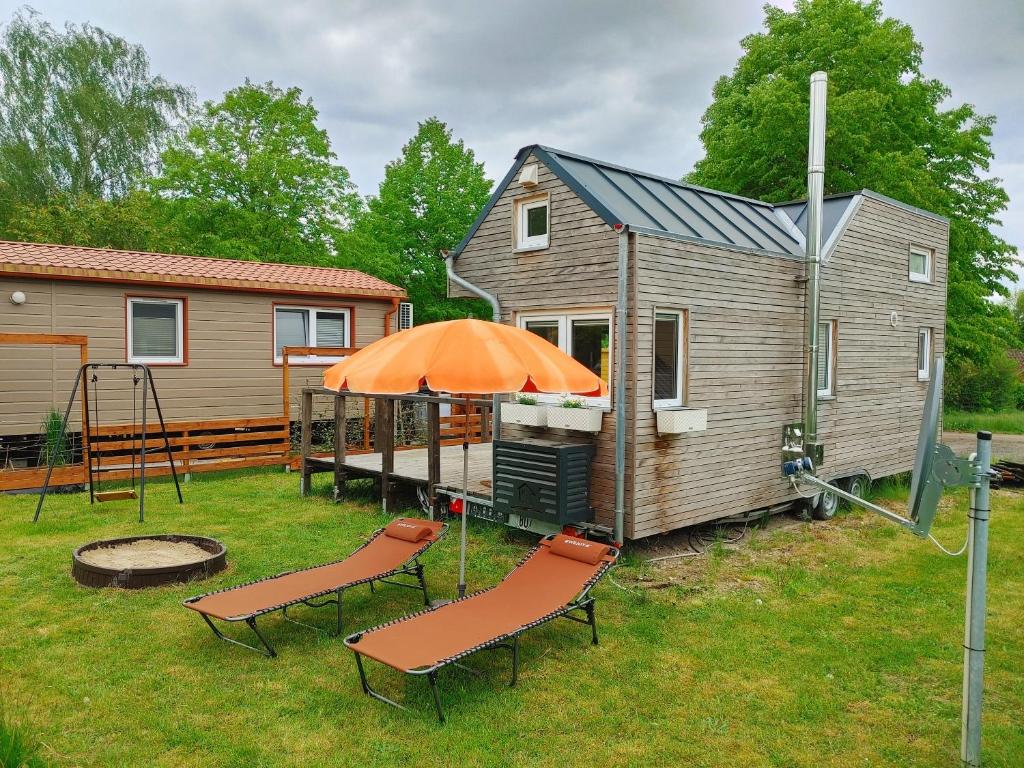 a tiny house with two chairs and an orange umbrella at MY LITTLE TINY HOUSE in Visselhövede