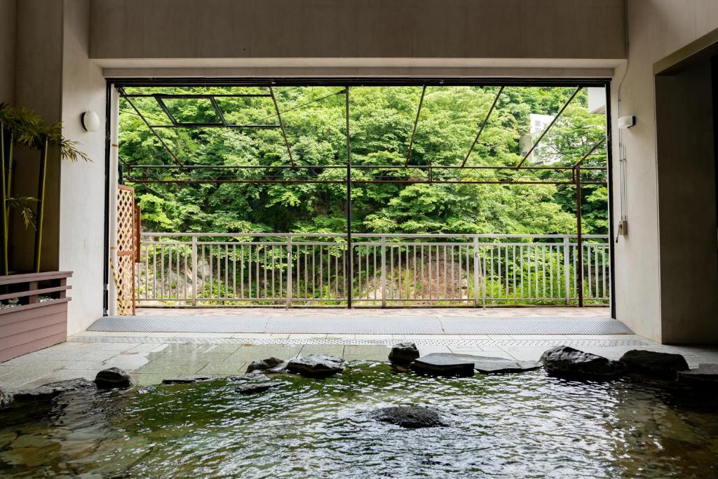 una camera con una piscina d'acqua con una grande finestra di Monogusa no Yado Hanasenkyo a Nikko