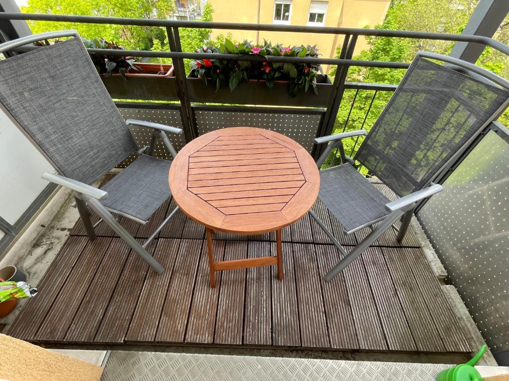uma mesa de madeira e 2 cadeiras numa varanda em 60sqm "Piece of heaven" in Munich's south em Munique