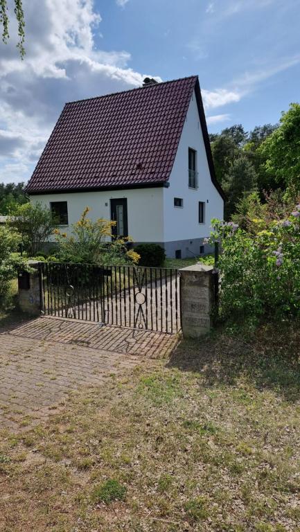 uma casa branca com uma cerca à frente. em Mecklenburgische Seenplatte - FH mit optionalem Steg und Ruderboot em Großzerlang