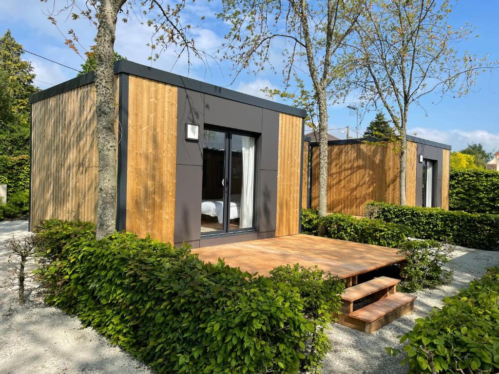 ein kleines Haus mit einem Holztisch im Garten in der Unterkunft CAMP'HOTEL in Mamers