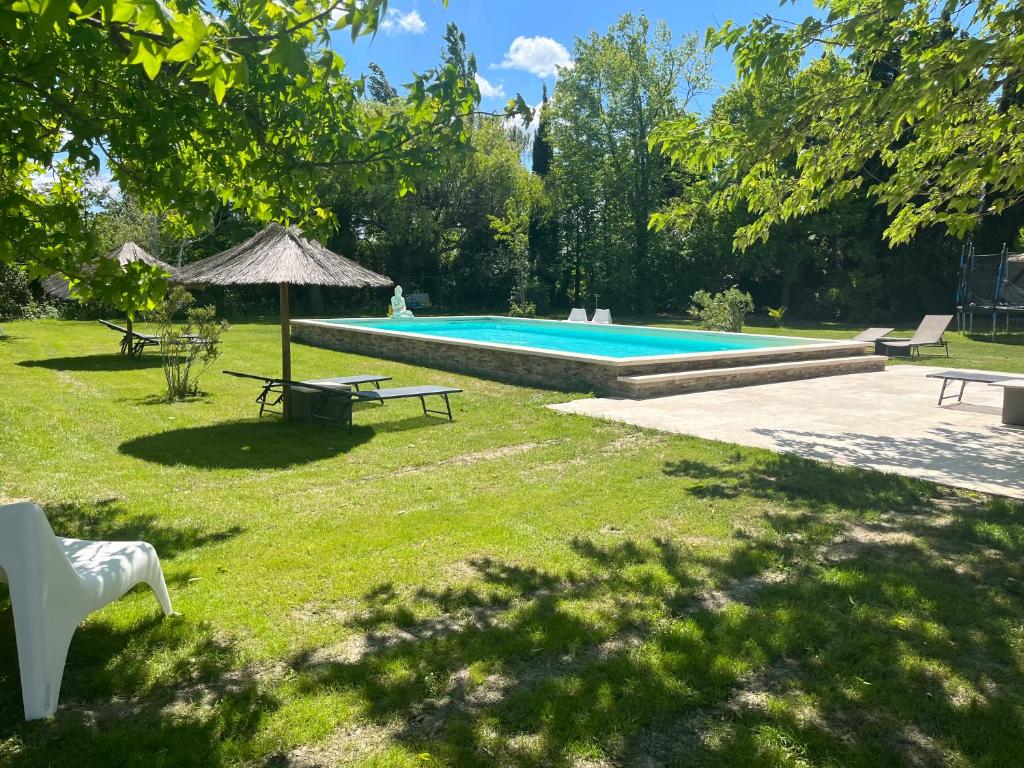einen Garten mit einem Pool mit einem Picknicktisch und einem Sonnenschirm in der Unterkunft Le jardin de Jade in Bédarrides
