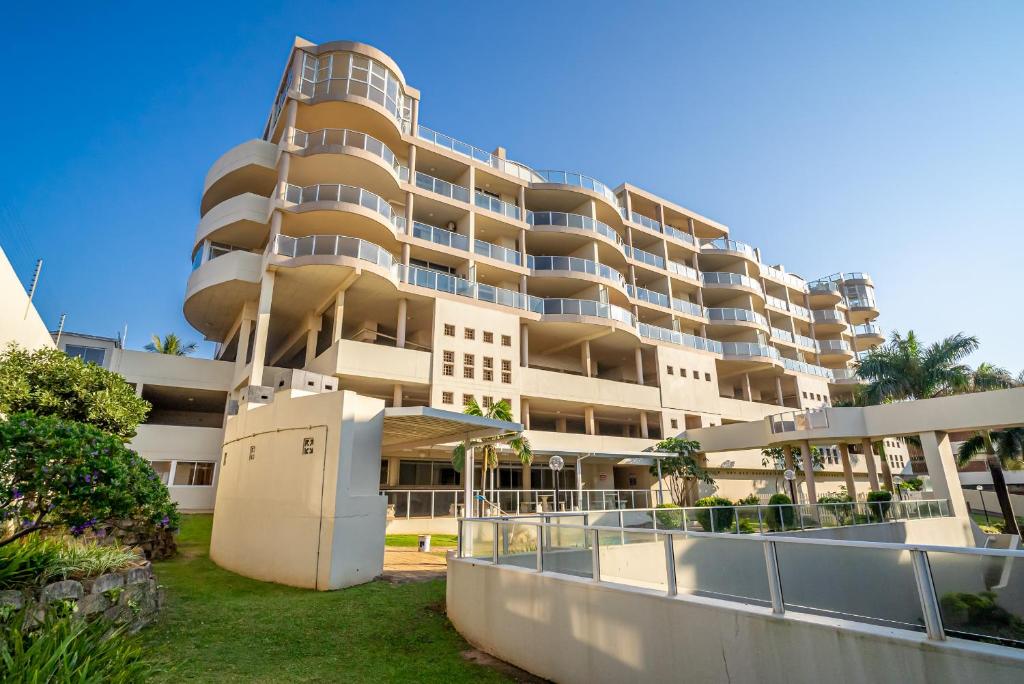 un gran edificio de apartamentos con césped delante en 304A Santorini -Margate RSA, en Margate