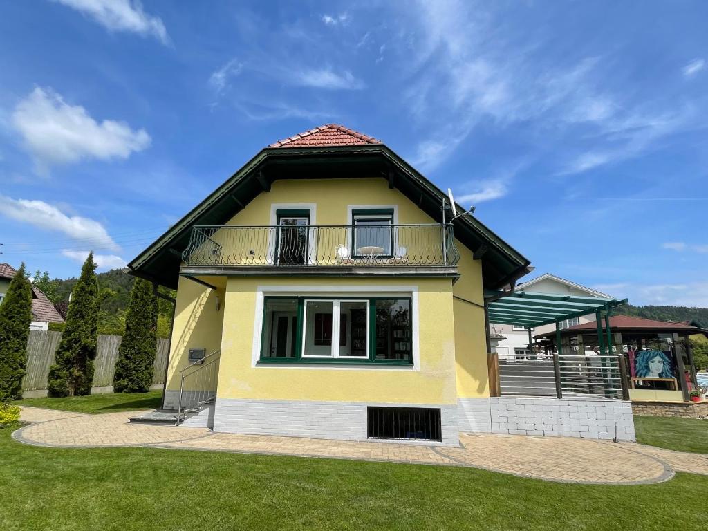 a yellow house with a balcony on a yard at APARTMENT Schlossbergblick in Griffen
