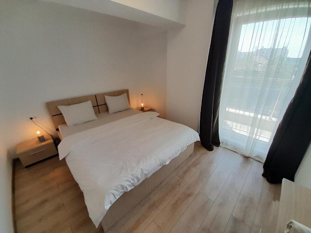 a bedroom with a white bed and a large window at Airplane Residence 1 in Otopeni