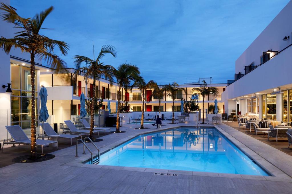 uma piscina num hotel com cadeiras e palmeiras em Courtyard by Marriott Santa Barbara Downtown em Santa Bárbara