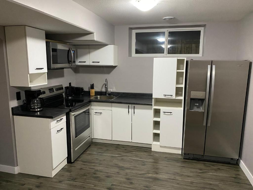 a kitchen with white cabinets and a stainless steel refrigerator at A cozy 1 bedroom suit in Saskatoon