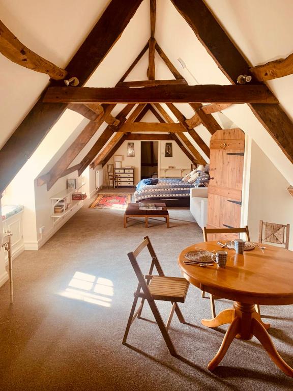 a large attic room with a table and a bed at Grange stables in North Cadbury