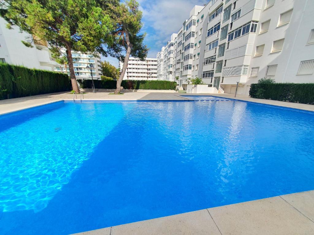 a large blue swimming pool in front of some buildings at 5 Salou,Playa,Piscina cento PARKING in Salou