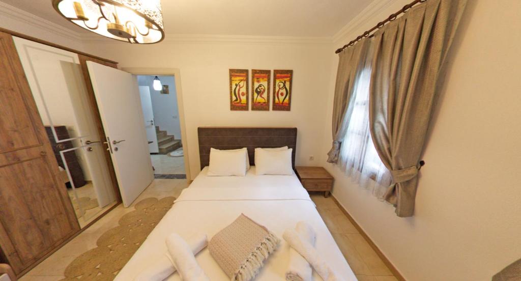 a bedroom with a bed with white sheets and a window at Castello Marmaris Holiday Home in Marmaris