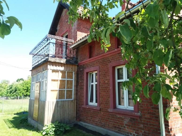 a red brick house with a balcony on it at Zofiówka in Stare Jabłonki