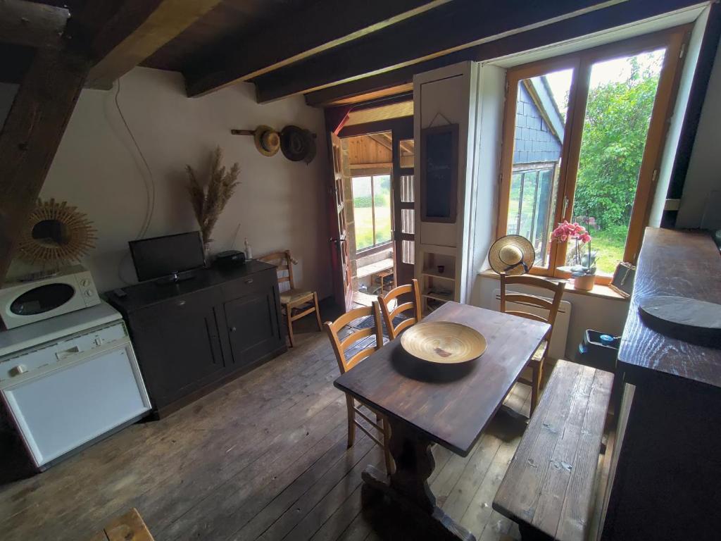 ein Wohnzimmer mit einem Tisch und einem Herd in der Unterkunft L'Aulnerie in La Chapelle-Cécelin
