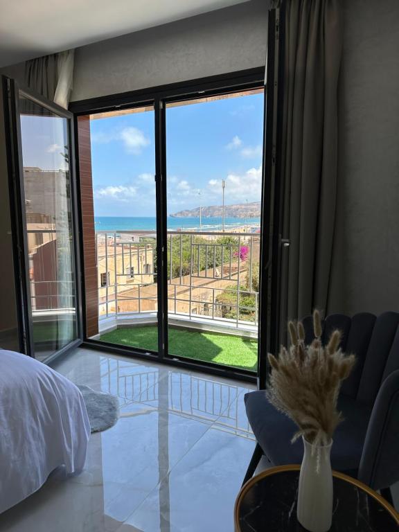 a bedroom with a large window with a view of the ocean at Bella Address Hotel Beach in Saïdia