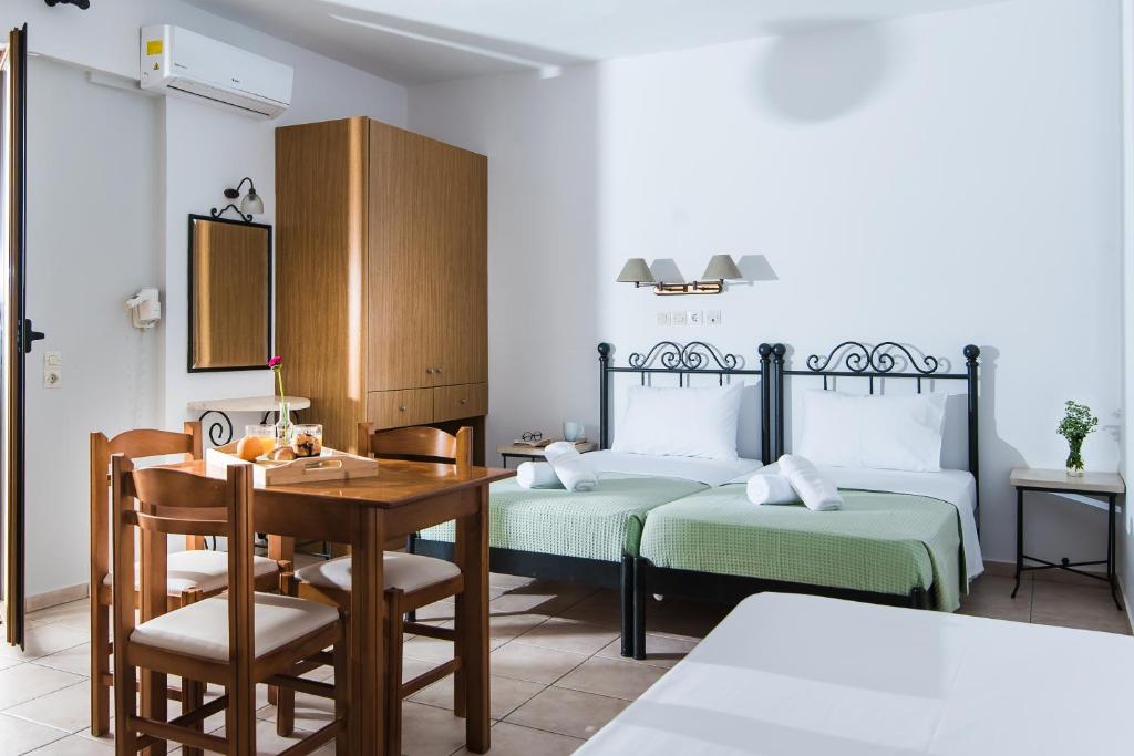 a bedroom with two beds and a table and a desk at Newcastle Studios by Estia in Malia