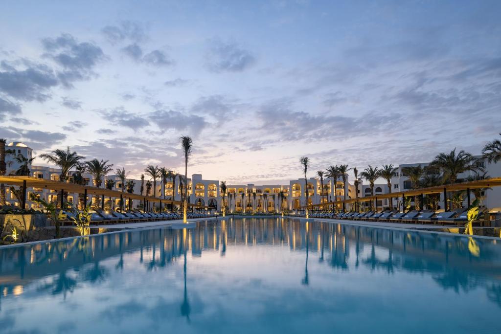 uma piscina num resort com cadeiras e palmeiras em Serry Beach Resort em Hurghada